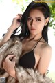 A woman in a black bikini and a fur coat.