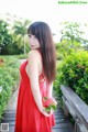 A woman in a red dress holding a flower.
