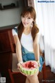 A woman sitting on a chair holding a slice of watermelon.