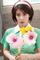 A woman in a green dress holding a bunch of flowers.