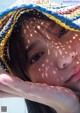 A young girl wearing a colorful hat on the beach.