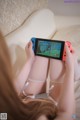 A woman sitting on a couch playing a video game on a Nintendo Switch.