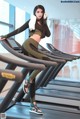 A woman is sitting on a treadmill in a gym.