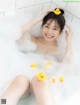 A woman sitting in a bathtub with rubber ducks.