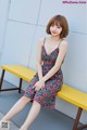 a woman sitting on a yellow bench wearing a floral dress