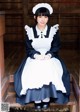 A woman in a maid outfit sitting on a wooden bench.