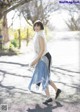 A woman walking down a street in a blue skirt.